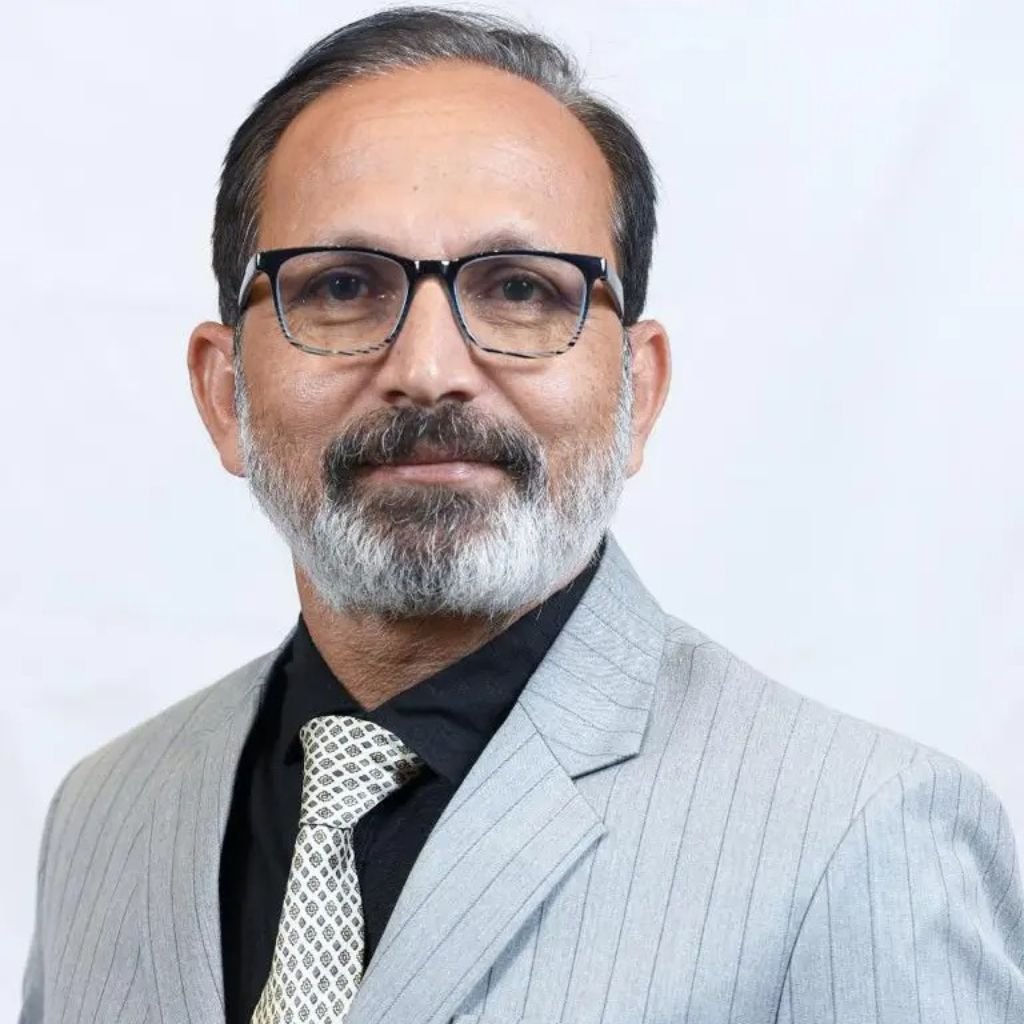Portrait of Ravi Wadje, a professional middle-aged Indian man in formal attire, standing confidently with a neutral dark background